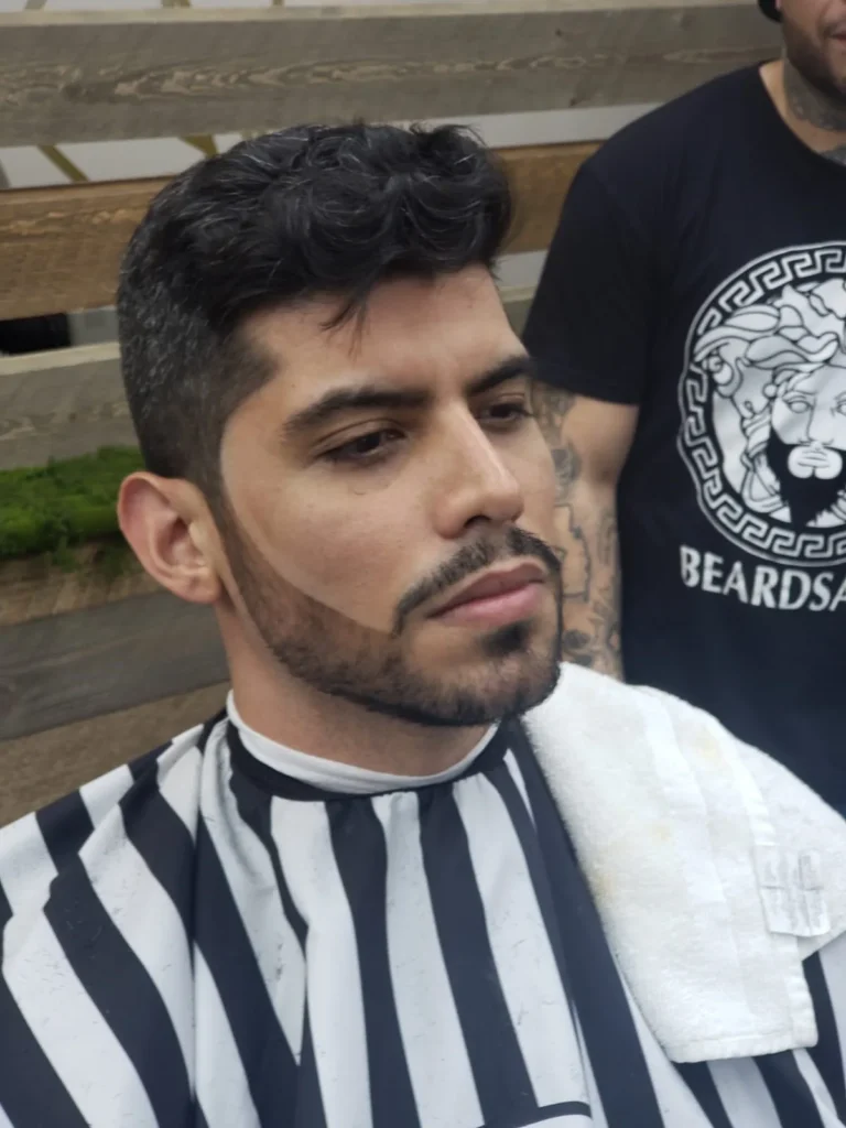 Man with a shaped beard and a tapered cut, standing in the shop