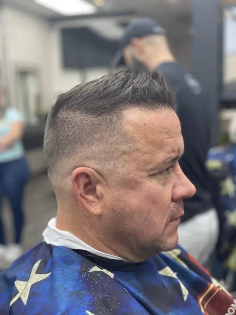 Man with brushed-back greying hair and tapered sides, side view