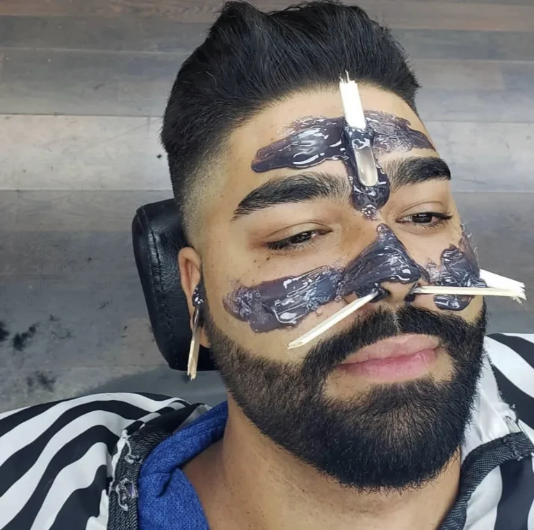 Customer with a black charcoal peel-off mask on during a facial