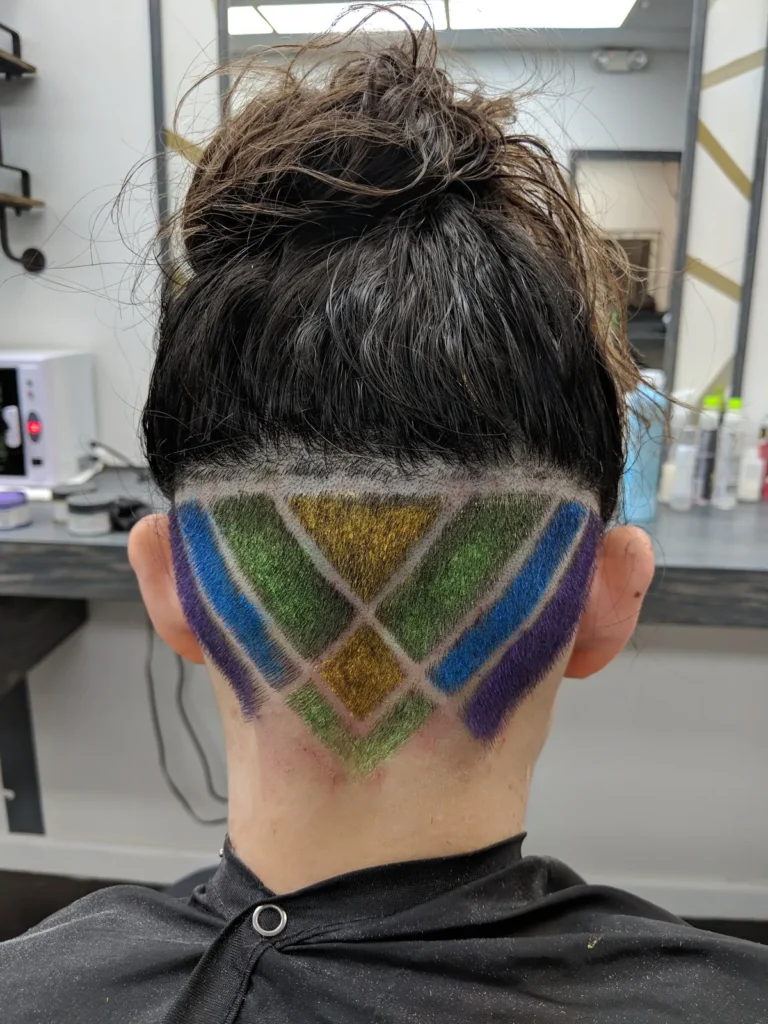 Back of a head with a green and blue diamond pattern shaved into the undercut