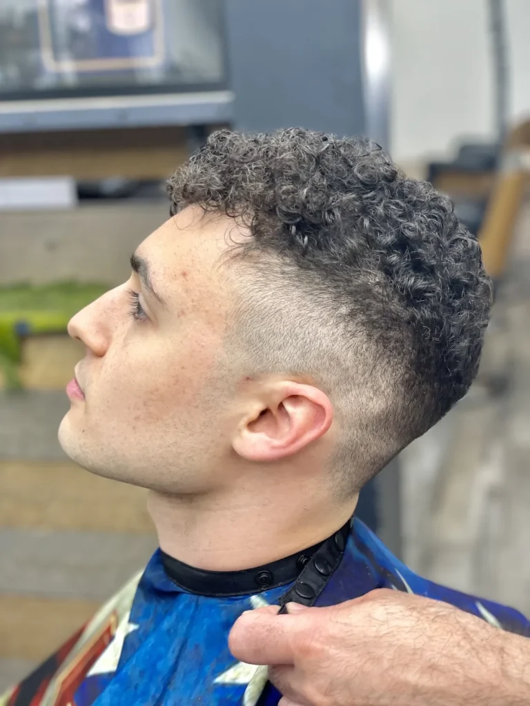 Young man with a curly crop and a high skin fade, side view