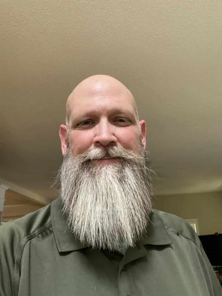 Smiling customer with a long white beard, shaped and trimmed