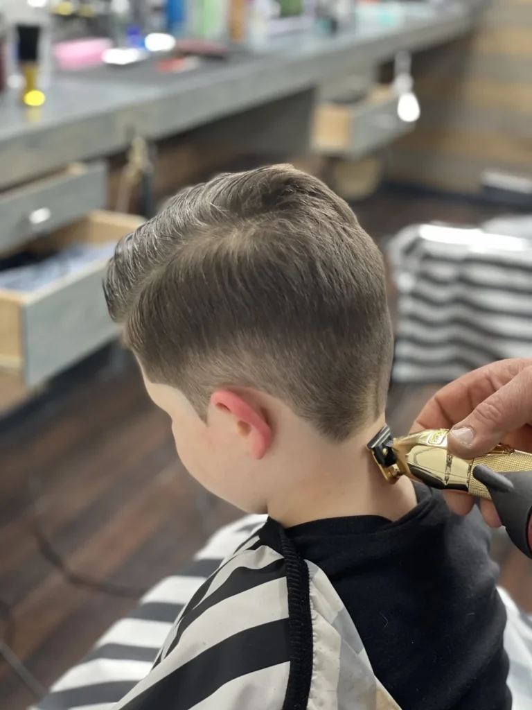 Barber running clippers up the back of a young boy’s head