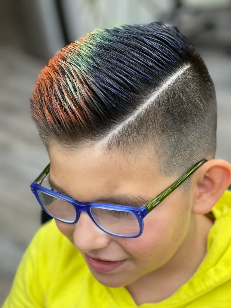 Boy in glasses with rainbow colour combed into a hard-part cut