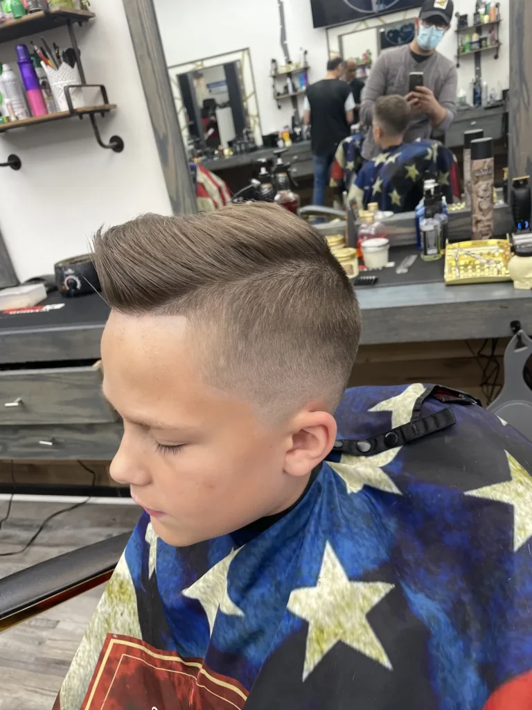 Boy with a side part and a skin fade, seated in the chair