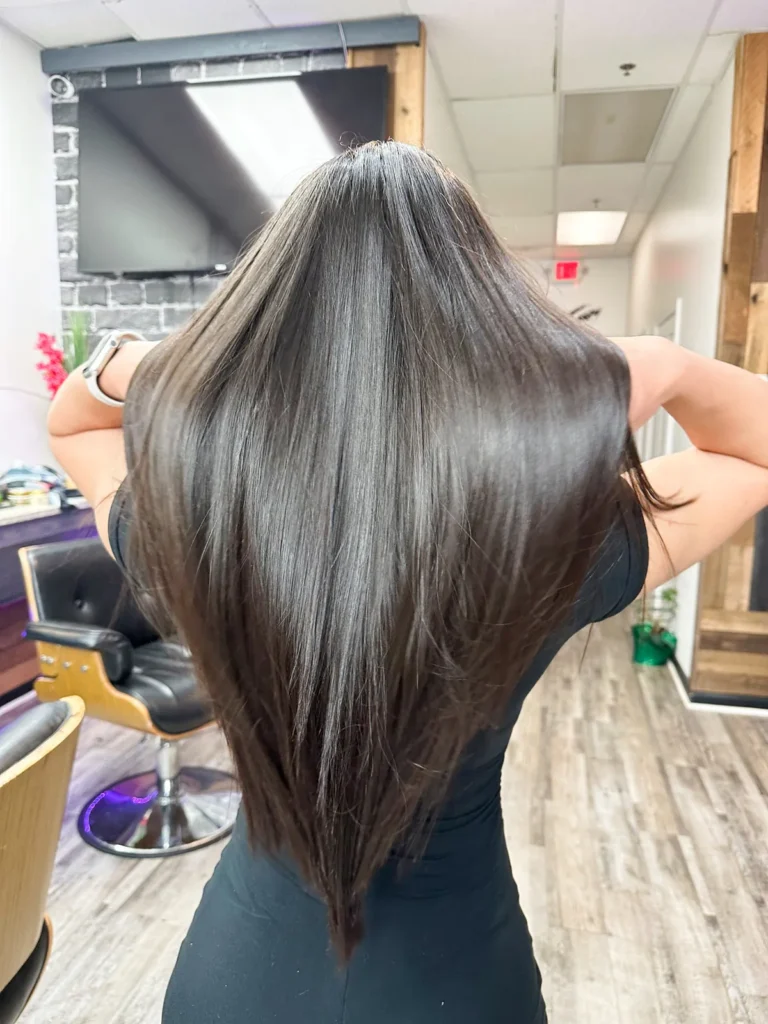 Long brown hair blow-dried smooth, seen from behind in the salon chair