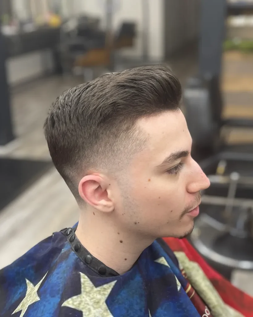 A fresh low fade with the top combed back, seen side on, at Milton Salon, Alpharetta