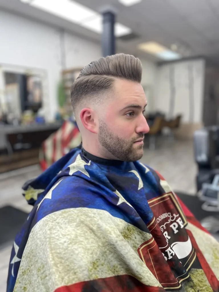 Man with a pompadour, tapered sides and a lined-up beard