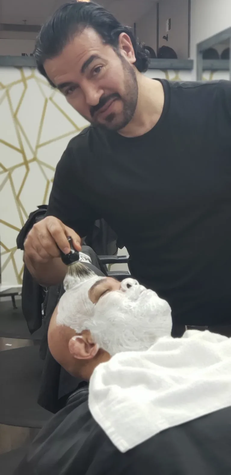 Customer reclined with shaving lather on, mid straight razor shave