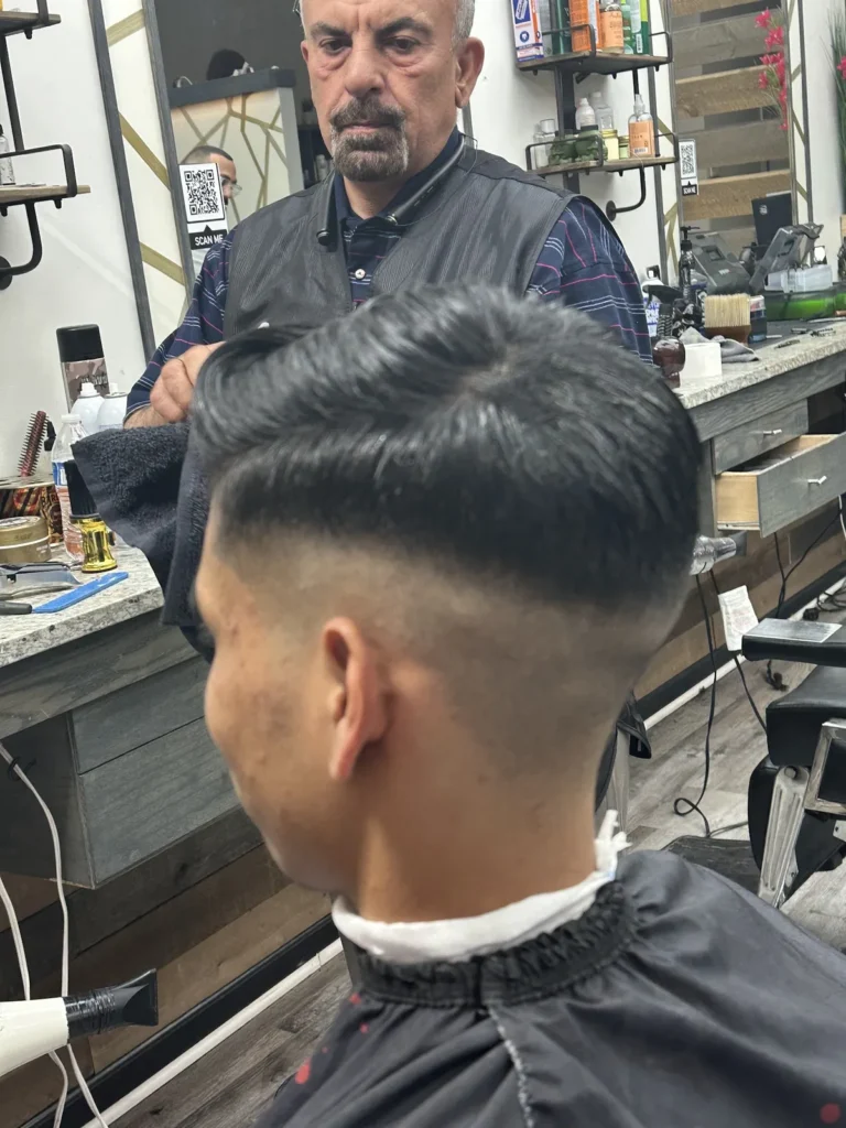 Back of a fresh taper fade, the barber and mirror behind
